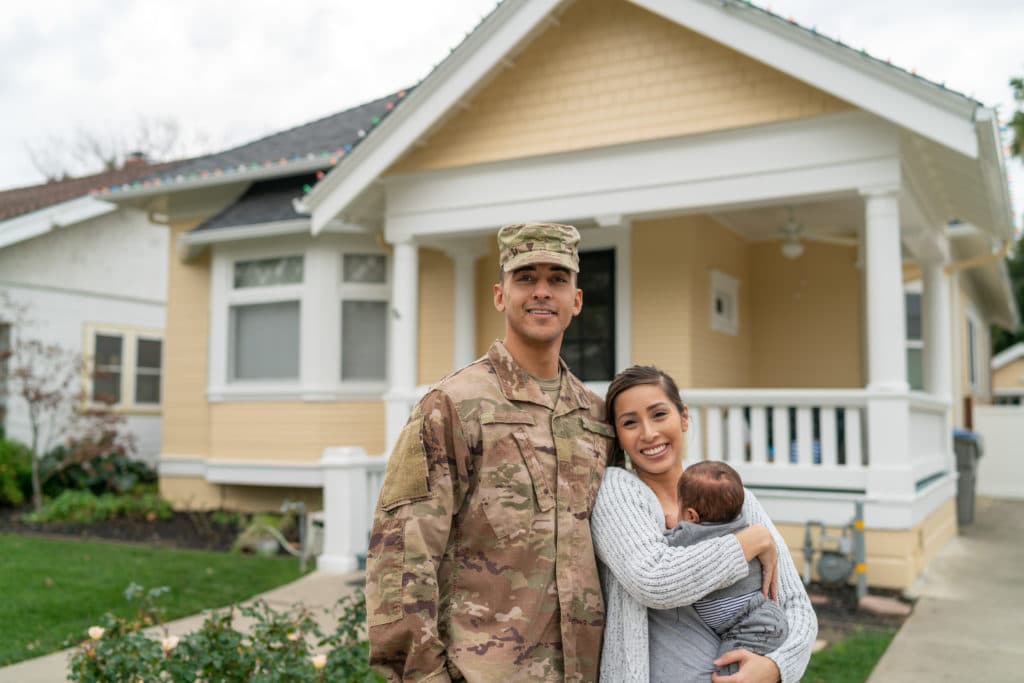 Military family in front of house.